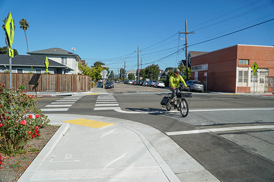 Image of person outside turning a corner on bicycle on a road next to the sidewalk