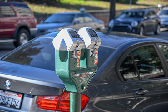 Image of two parking meters with cars parked at them