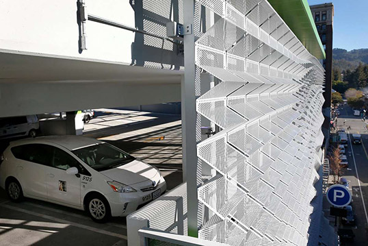 Image of multi-story parking garage with shaded wall to diffuse sunlight on parked cars.