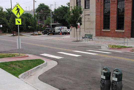 Image of crosswalk on empty road including two curb bulbs and yield sign.
