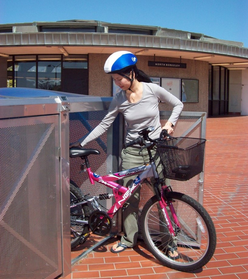 Photo of a person parking a bike in a bike locker at the North Berkeley BART station.