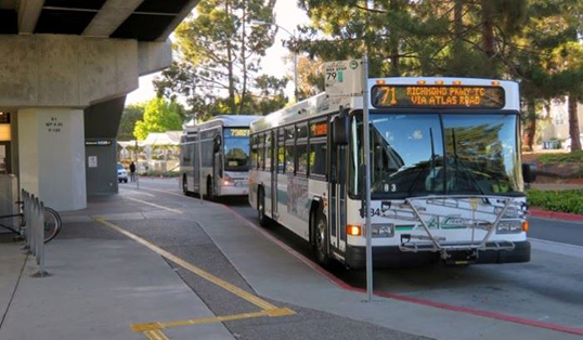 An AC Transit bus in front of the entrance to a BART station.