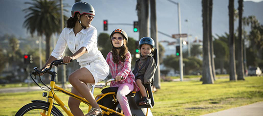 An adult transporting two children on an electric bike