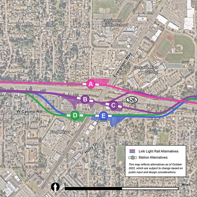 This map shows the five Evergreen Link station alternatives and their respective footprints. Station alternative A is symbolized by a pink circle labeled A. The station is located on the northwest corner of the intersection of Evergreen Way and SR-526. The station’s footprint, symbolized by a faint pink shape, sits between Beverly Lane and Evergreen Way. The station’s light rail track alternative is symbolized by a pink line and sits just north of and runs parallel to SR-526. Station alternative B is symbolized by a purple circle labeled B. The station is located southwest of the intersection of SR-526 and Evergreen Way. The station’s footprint, symbolized by two faint purple rectangle, extends south towards Casino Road. The station alternative’s light rail track, which is symbolized by a purple line, runs west to east and crosses over Evergreen Way and then crosses north over SR-526 before running parallel to SR-526 east.       Station alternative B is symbolized by a purple circle labeled B. The station is located southwest of the intersection of SR-526 and Evergreen Way. The station’s footprint, symbolized by two faint purple rectangle, extends south towards Casino Road. The station alternative’s light rail track, which is symbolized by a purple line, runs west to east parallel to SR-526 then crosses over Evergreen Way and then crosses north over SR-526 before running parallel to SR-526 east. Station alternative C is symbolized by a purple circle labelled with a C. The station is located southwest of the intersection of Evergreen Way and SR-526. The station’s footprint is symbolized by a small and faint purple square. The station alternative’s light rail track, which is symbolized by a purple line, runs west to east parallel to SR-526 and crosses over Evergreen Way before entering station alternative C then continuing east and crossing north over SR-526.  Station alternative D is symbolized by a green circle labeled D. The station is located southwest of the intersection of Casino Road and Evergreen Way. The station’s footprint, symbolized by faint green half-circle, extends south towards Fred Meyer. The station alternative’s light rail track, which is symbolized by a green line, runs west to east parallel to SR-526 before curving south over W Casino Road and entering the station, crossing Evergreen Way, then curving back north over SR-526. Station alternative E is symbolized by a blue circle labeled E. The station is located southeast of the intersection of Casino Road and Evergreen Way. The station’s footprint, symbolized by a faint blue triangle, extends southeast towards Holly Drive. The station alternative’s light rail track, which is symbolized by a blue line, runs west to east parallel to SR-526 before curving south over W Casino Road and crossing over Evergreen Way, entering the station, then curving back north over SR-526.